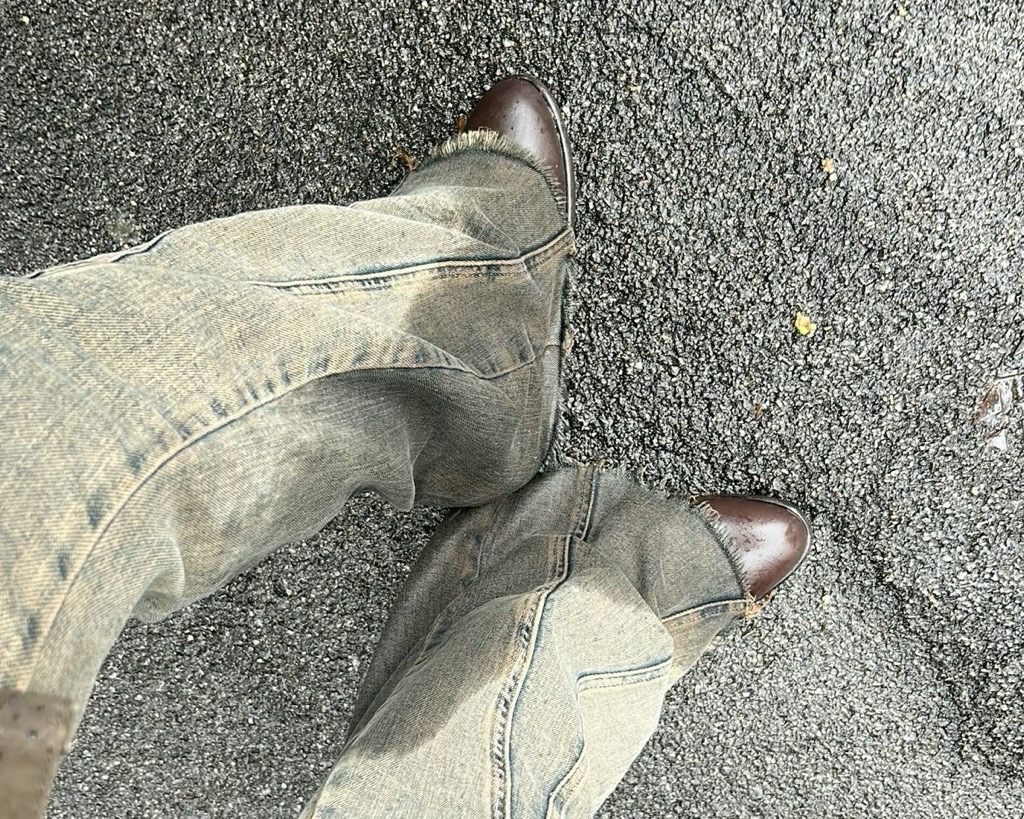 Ljusa jeans och bruna boots på asfalt